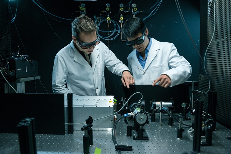 Two researchers examine an experimental laser set-up