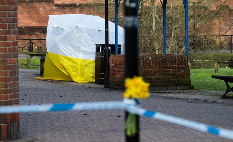 Flowers are pictured in front of a police forensics tent covering the bench connected to the Sergei Skripal nerve agent attacks