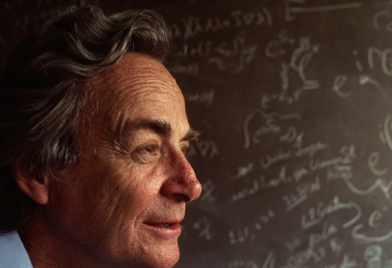Richard Feynman stands in front of a blackboard strewn with notations in his Los Angeles Laboratory.