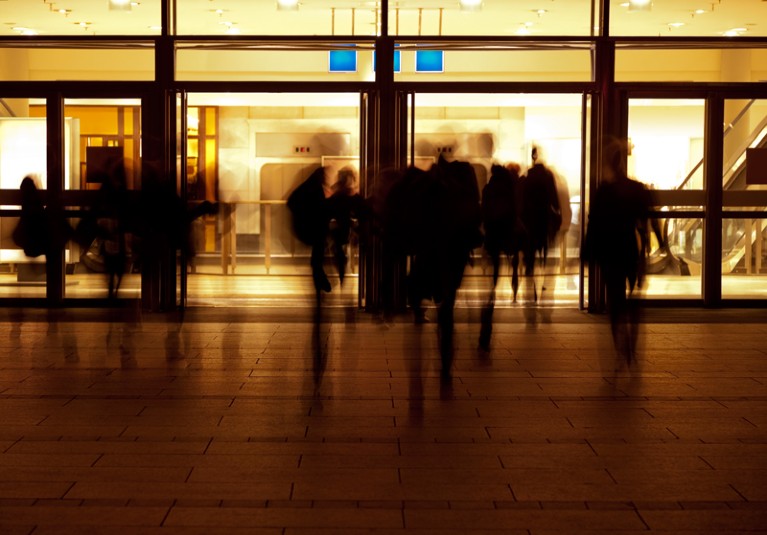 Silhouettes of people in front of building entrance at night.