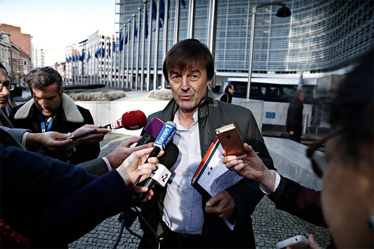 Nicolas Hulot talks into reporters' microphones on a busy street in 2018