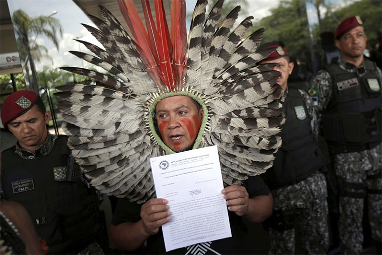 Indigenous leader Kaigang Chief Kreta,wearing a ceremonial headdress,holds up a letter with demands outside presidential offices