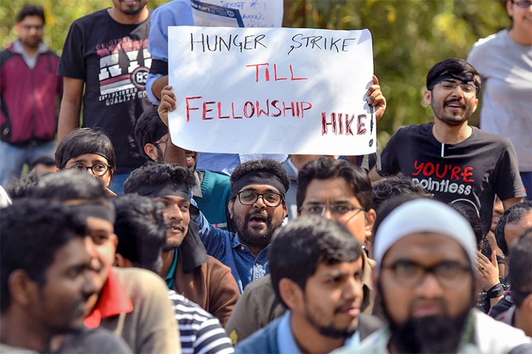 An Indian student holds up a sign reading 'Hunger strike till Fellowship Hike' during a protest.