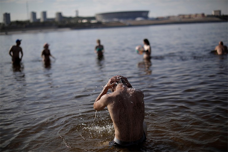 A man cools himself off in the water at the banks of Volga River, Russia, 2018.