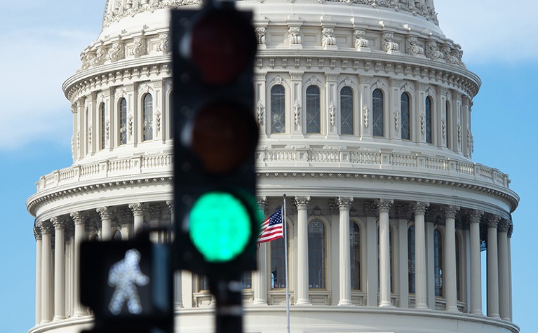 A traffic light lit green with a walk sign in front of the US Capitol Building in Washington DC, USA