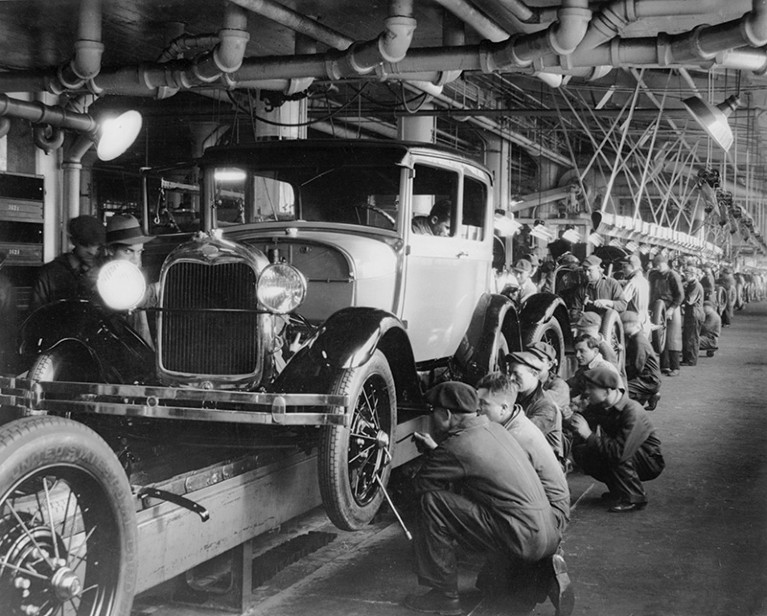 A black-and-white photo of cars in a production line.