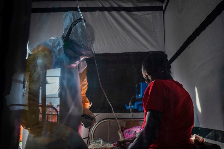 Health workers wearing protective gear check on Ivette Adania, 24, a mother of four whose husband died of Ebola