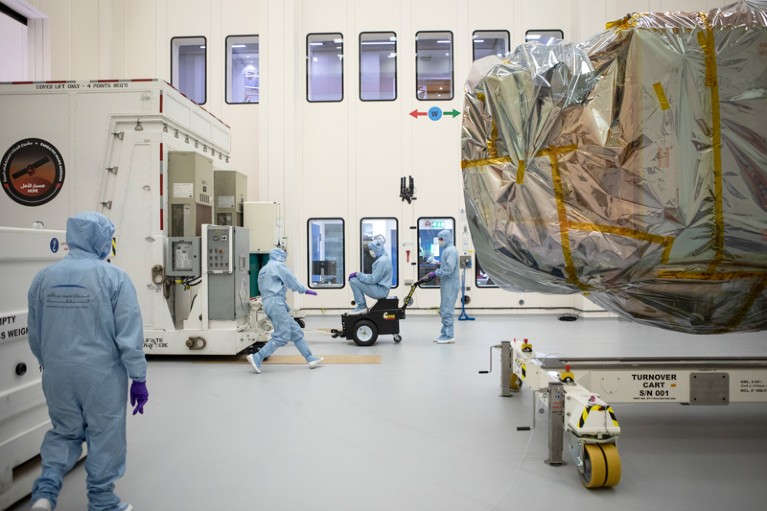 Workers in cleanroom suits move a crate around the Hope probe at The Mohammed Bin Rashid Space Centre