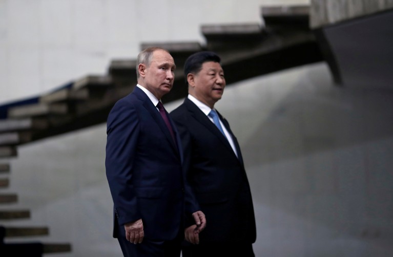 Vladimir Putin and Xi Jinping walk past a spiral flight of stairs