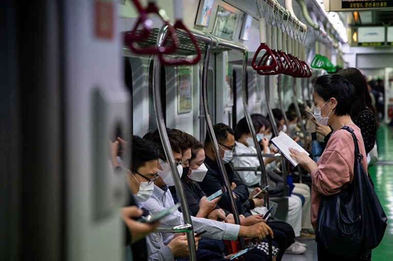 Passengers wearing protective masks ride a subway train in Seoul, South Korea