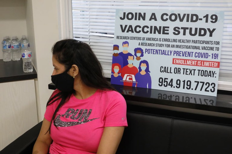 A person wearing a protective mask sits after participating in clinical trials for a COVID-19 vaccine