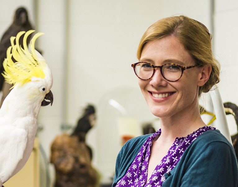 Lucy Aplin stands next to a cockatoo exhibit in a museum
