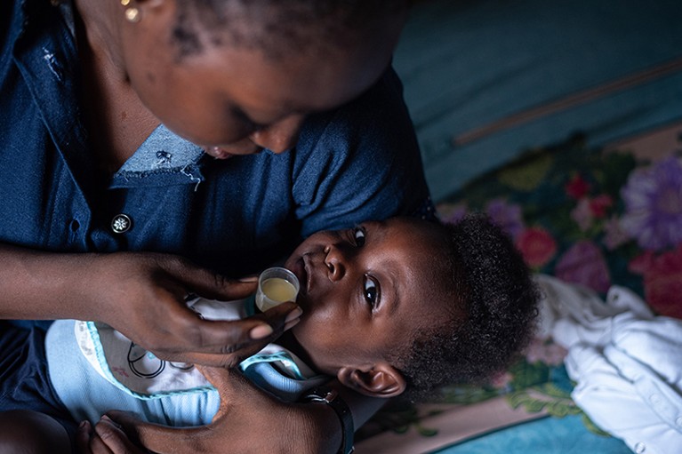 Sean smiles at the camera as his mother prepares to give him his medication