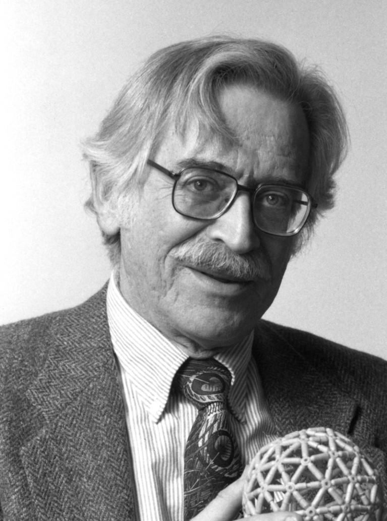 Black and white portrait of Donald Caspar holding a molecular model