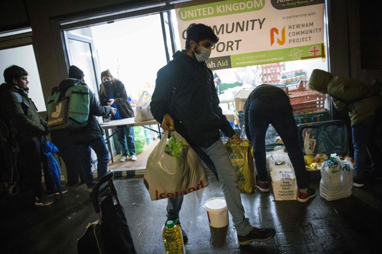 An international student leaves after collecting food packages from a food bank at night