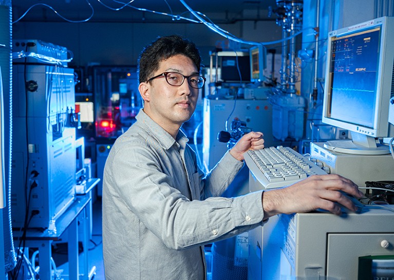 Ken-ichi Otake standing in front of computer in lab