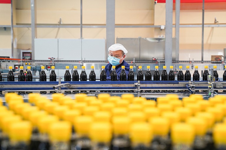 A worker checks bottled soy sauce at a factory