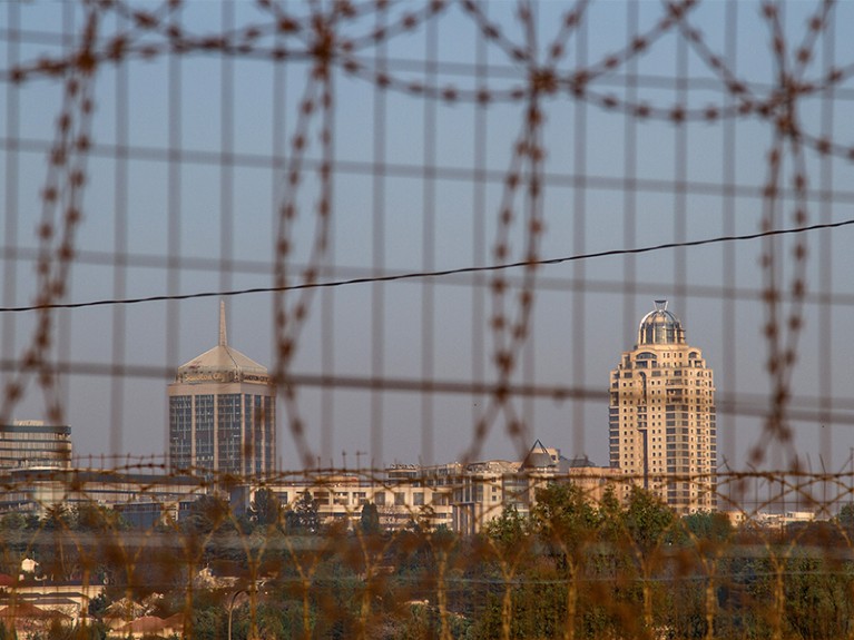 The city skyline stands beyond razor wire bordering the perimeter of Alexandra township in Johannesburg, South Africa.