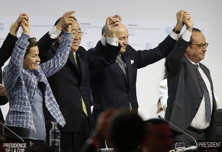Leaders raise their hands after the adoption of a historic global warming pact at the COP21, Paris.