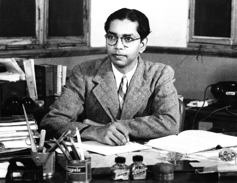 Black and white photograph of a young C.R. Rao writing at a desk