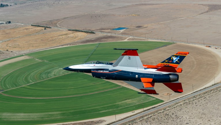 A test military aircraft that can be controlled by AI simulator flying over a circular crop field in California