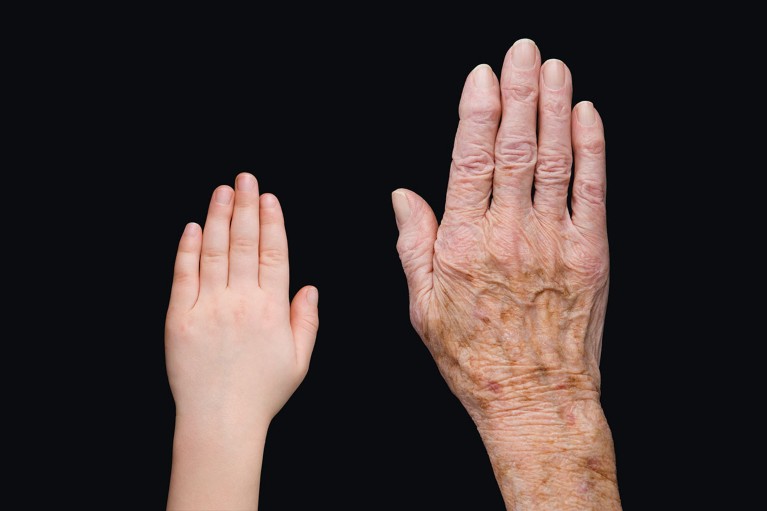 Young and old hands on a black background show the contrast of aging.