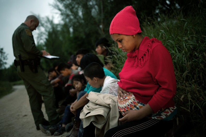 A pregnant woman and other migrants are apprehended by a Border Patrol agent