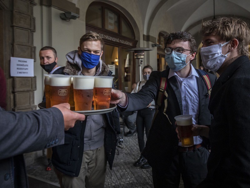 People drink beer at an outdoor seating section of a pub, as the Czech government lifted more restrictions.