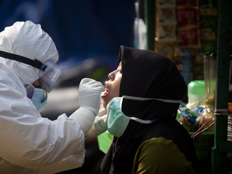 A health worker dressed in a personal protective equipment (PPE) suit is seen getting a swab test from a trader.