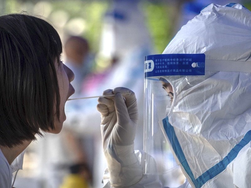 A Chinese epidemic control worker wears a protective suit as she performs a nucleic acid swab test for COVID-19.