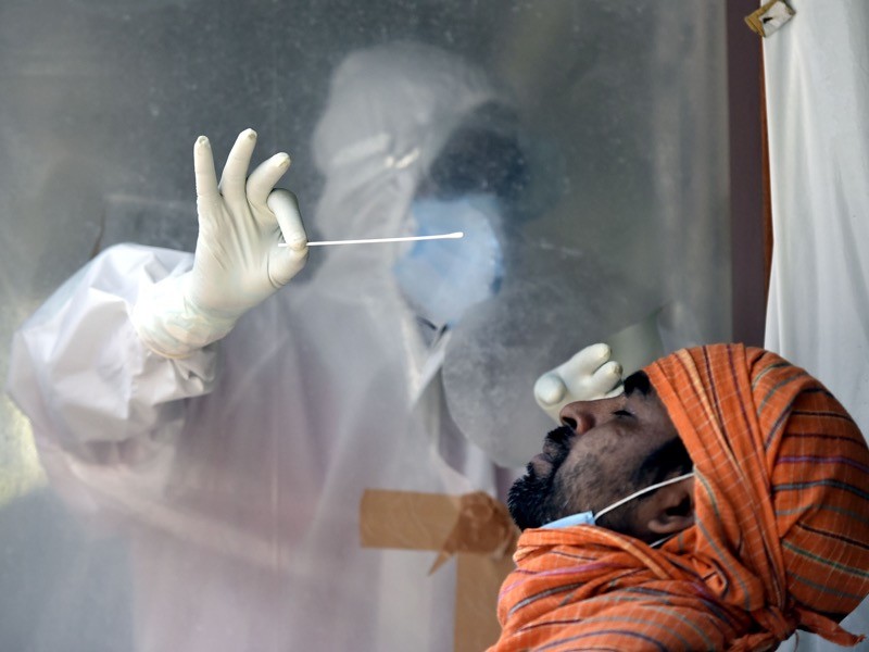 A health worker collects a swab sample from a man to test for coronavirus infection, New Delhi, India.