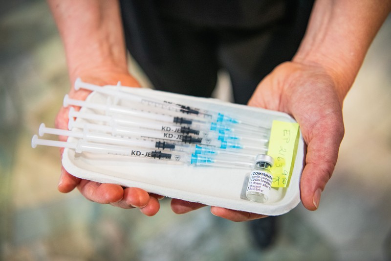 A medial worker holds a tray with syringes and a vial of Pfizer-BioNTech's vaccine
