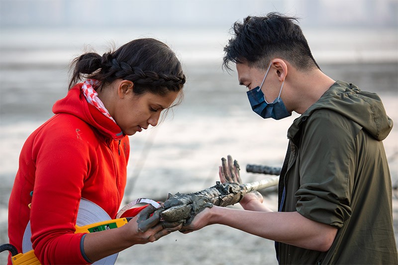Photo of Nicole Khan and PhD student Howard Yu in the mudflats of the Mai Po Nature Reserve.