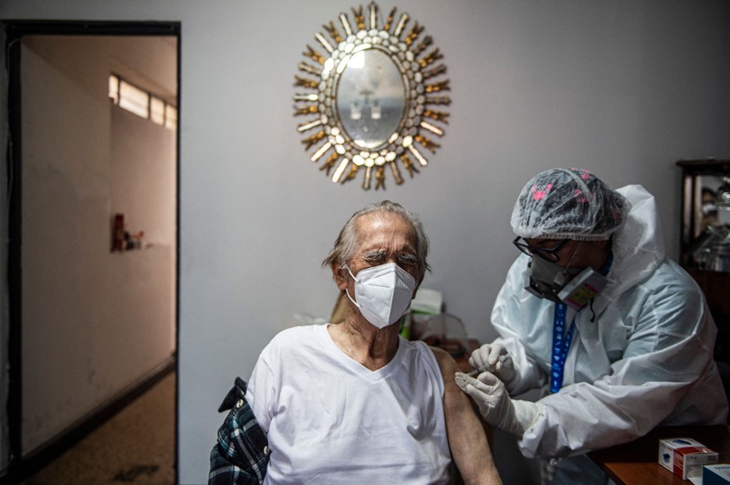 A health worker gives an older man a dose of the Pfizer–BioNTech COVID-19 vaccine