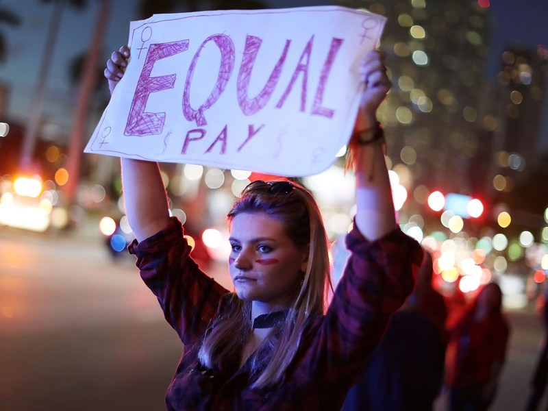 Clarissa Horsfall holds a sign reading, 'Equal Pay,' as she joins during 'A Day Without A Woman' demonstration, Miami, US.