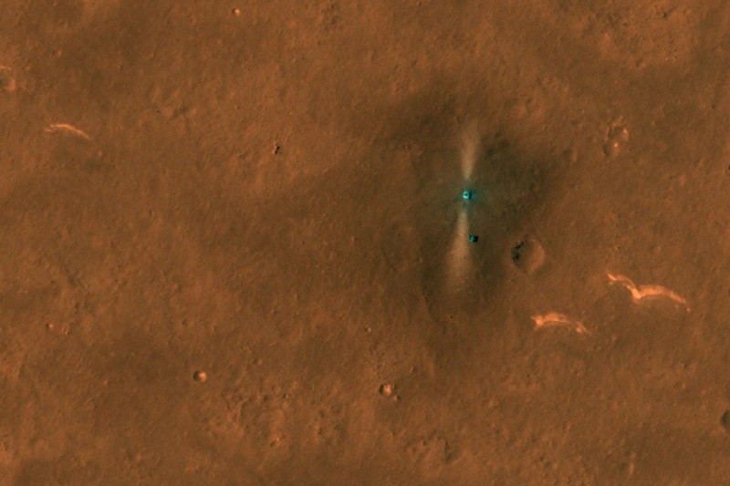 Surface of Mars with the Zhurong Mars rover surrounded by a blast pattern and its parachute and backshell lying a distance away