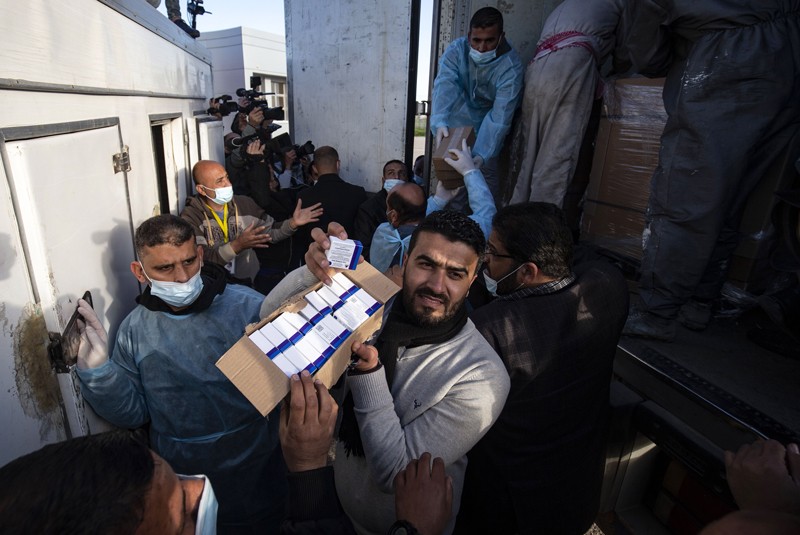 Workers unload boxes of the Sputnik vaccine from a truck in the Gaza Strip