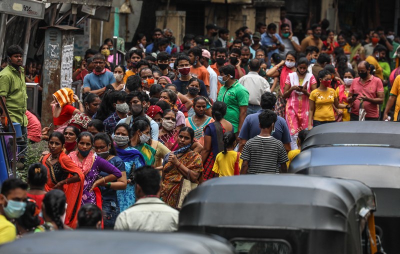 A crowd of people queue on a roadside to receive a covid-19 vaccine during a mass vaccination drive in Mumbai