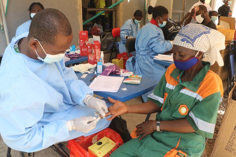 A health worker takes the blood sample of a waste bin worker for an HIV/AIDS test