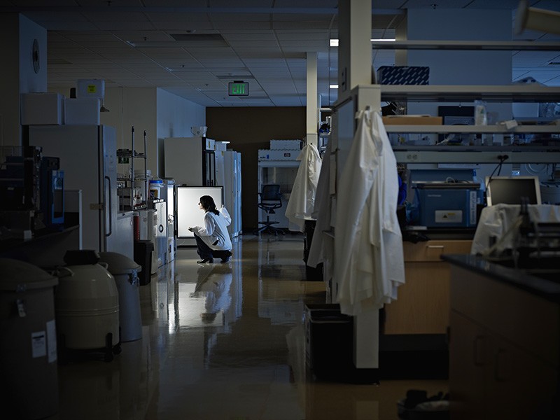 A scientist working alone at night in a darkened lab.