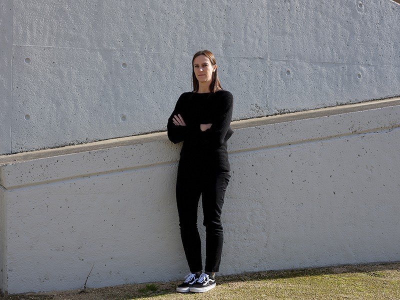 Danielle Anderson leaning against a concrete wall outside.