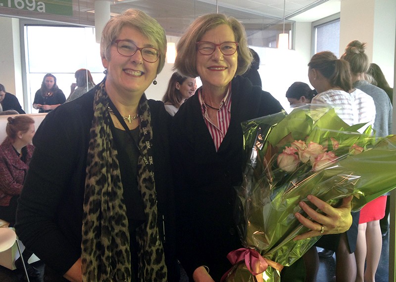 Rosemary Guyatt with a bouquet of flowers at her going party day from her previous job, standing with a colleague.