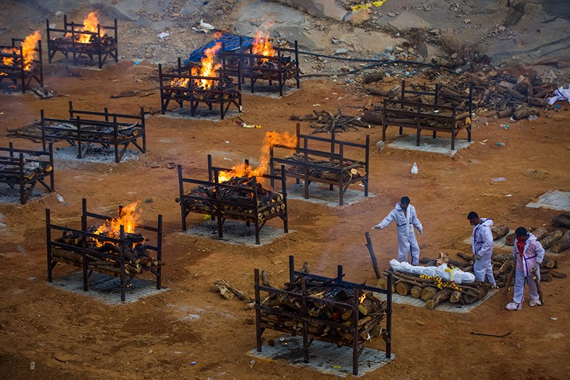 Men wearing PPE perform the last rites in a quarry repurposed to cremate the dead due to COVID-19 in Bengaluru, India.