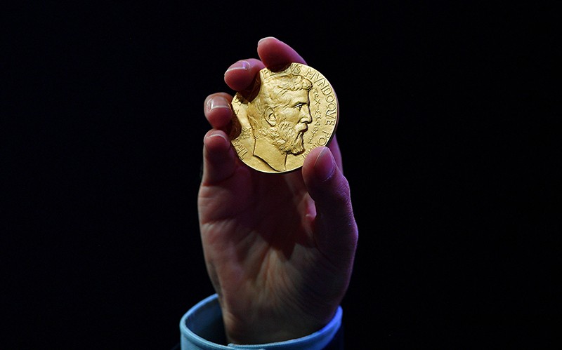 A new Fields Medal for Mathematics is held up for show in Caucher Birkar's hand in Brazil 2018.