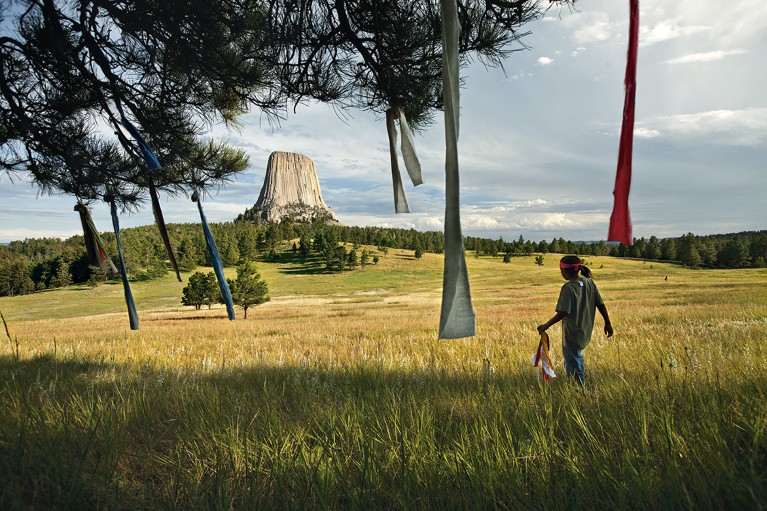 A boy places prayer flags in a tree near Devils Tower in Wyoming.