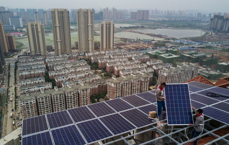 Workers install solar panels on a high-rise building in Wuhan, China.