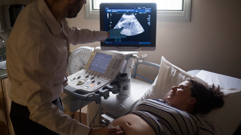 A doctor gives a pregnant woman an ultrasound scan