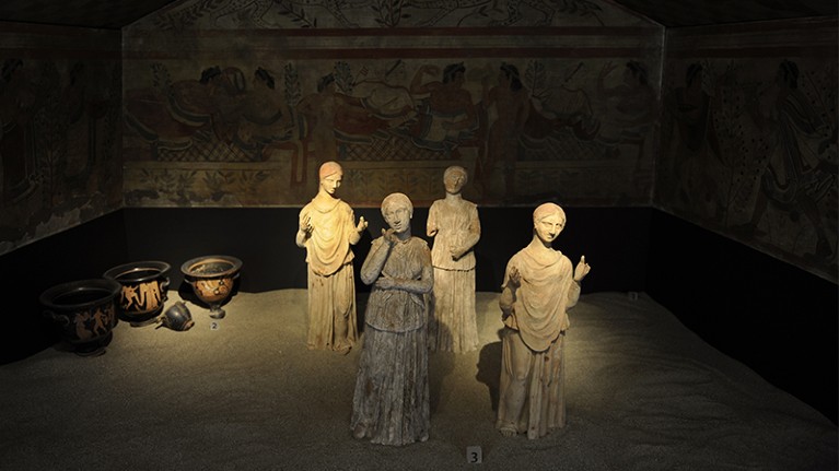 Reconstruction of the Etruscan Tomb of the Leopards. At centre are 4 lit statues of female mourners in different poses.