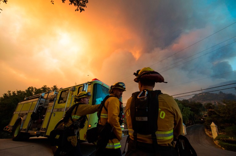 Firefighters monitor smoke and flames from a wildfire in California