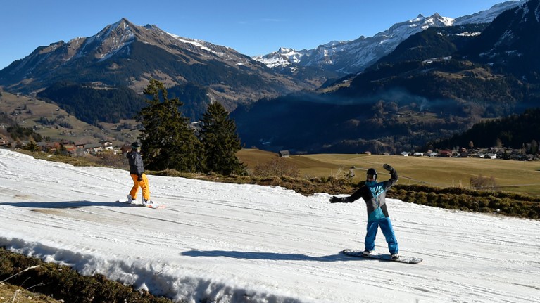 Tourists ski on a thin layer of snow in the Alps